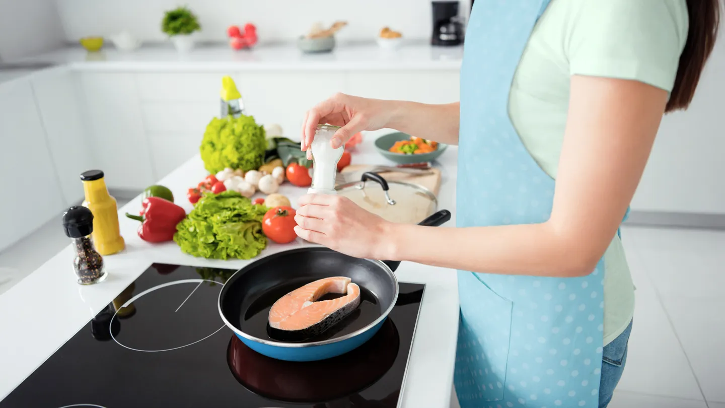 woman cooking salmon in her kitchen