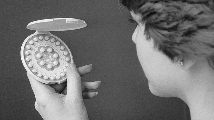 a woman holding birth control pills
