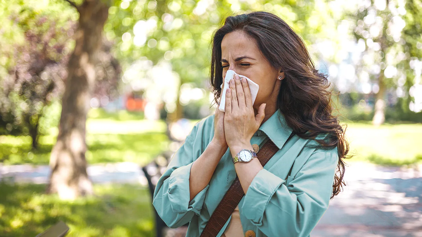 woman sneezing outdoors