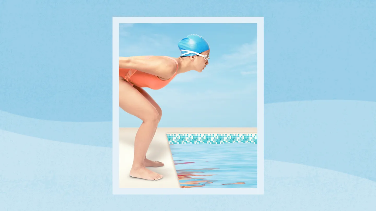 woman about to jump in outdoor pool cap and goggles
