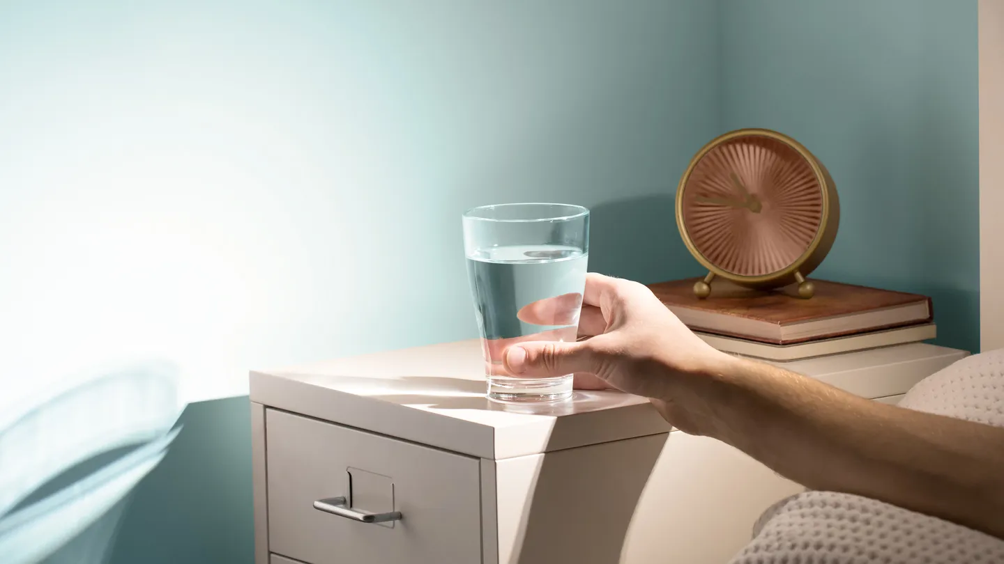 hand reaching for glass of water bedside table morning