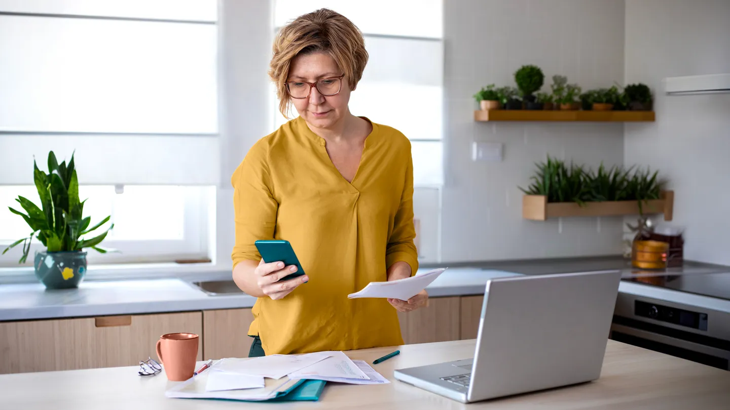 mature woman calling her health insurance company in her kitchen