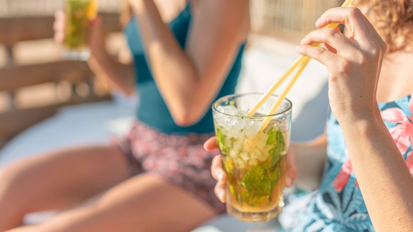 two women friends enjoying ice tea poolside in the summer