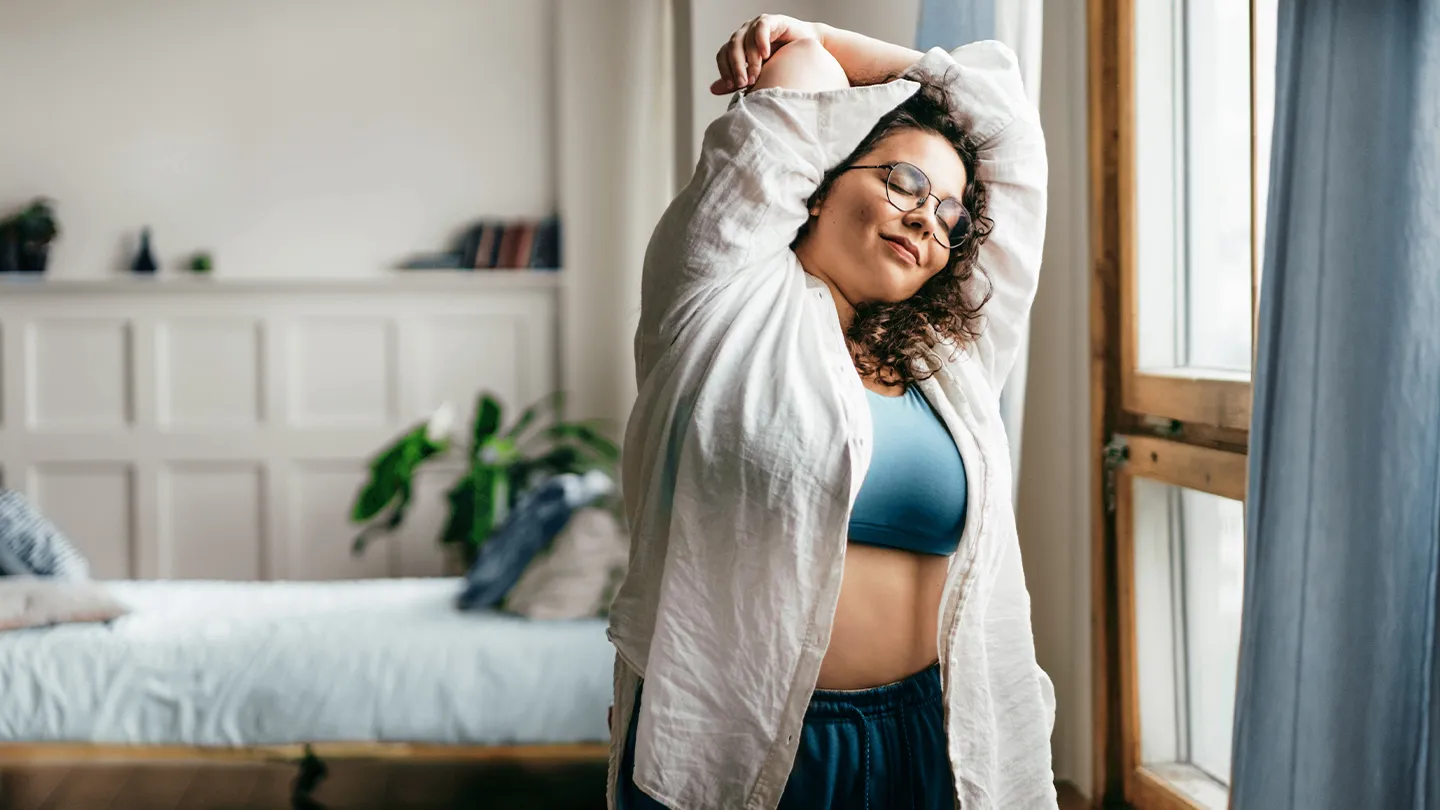 happy woman stretching in front of window