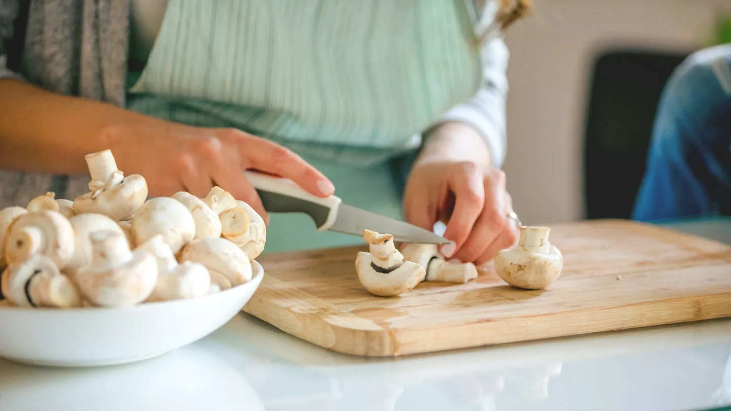 woman in kitchen cutting mushrooms