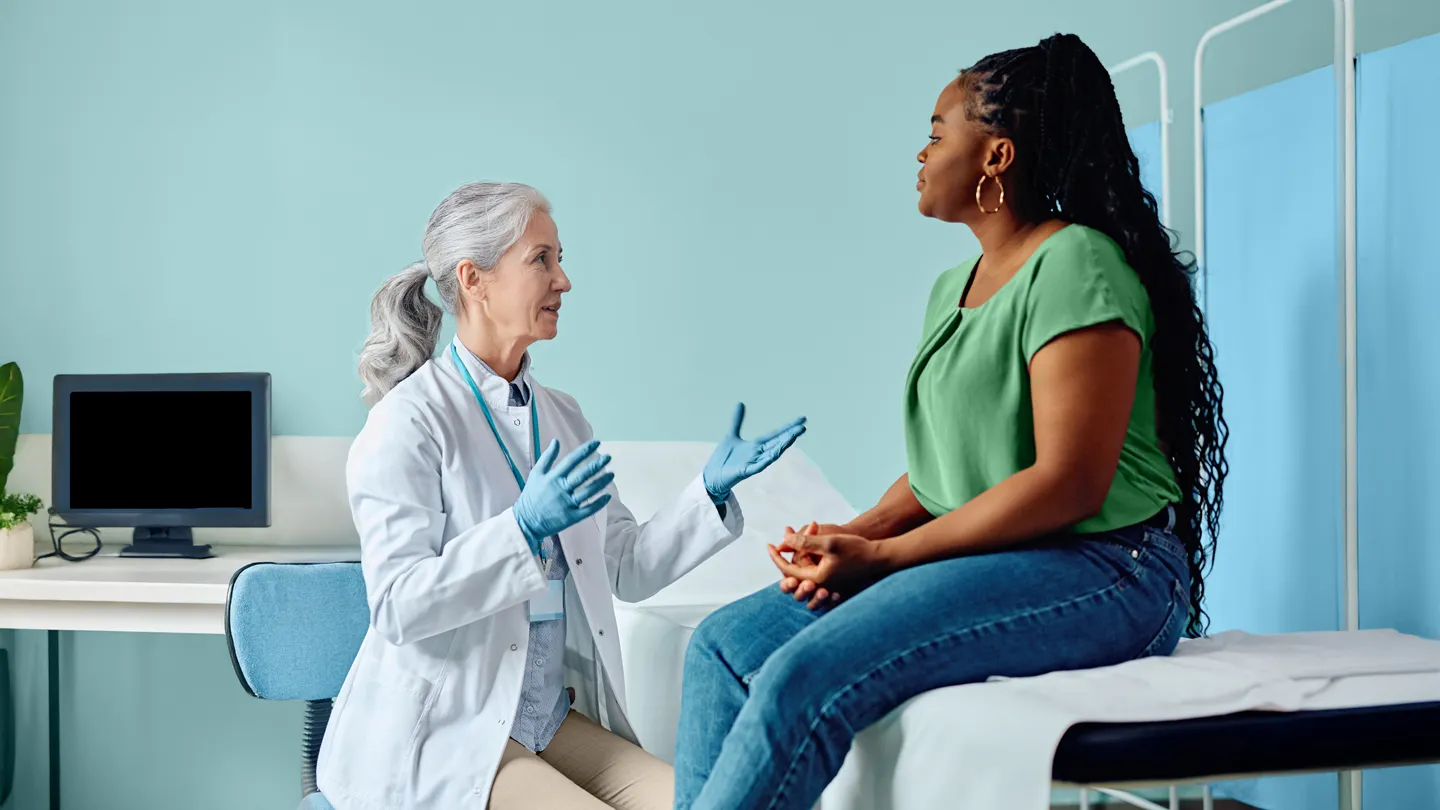 Female genecologist talking to black woman during medical examination