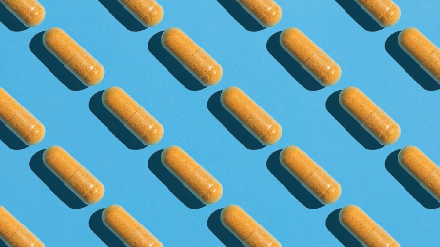 orange yellow coenzyme q10 supplement capsule pills on blue