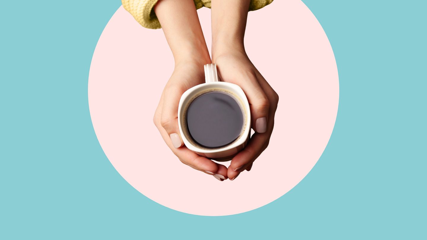 hands holding a cup of black coffee shot from above