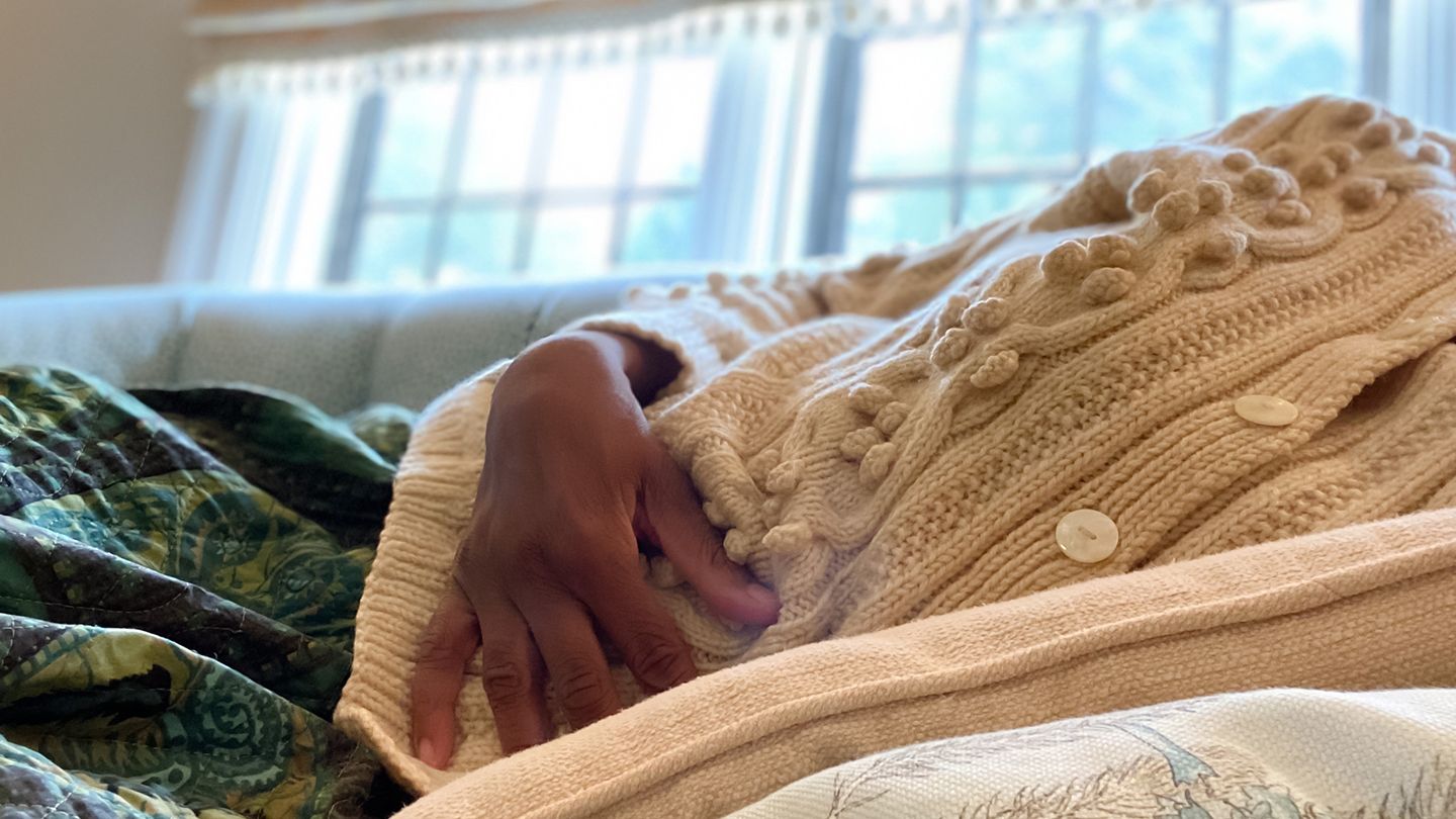 black woman holding stomach in pain on couch