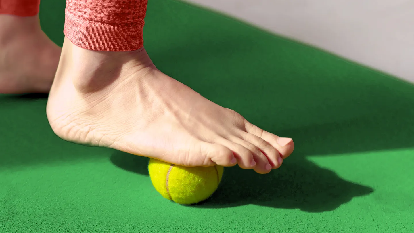 foot using tennis ball therapy on mat