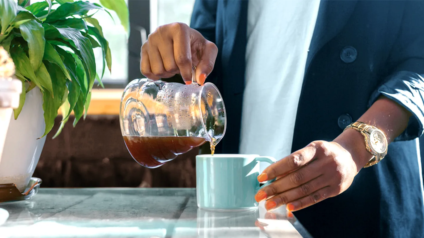 black woman pouring a mug of coffee