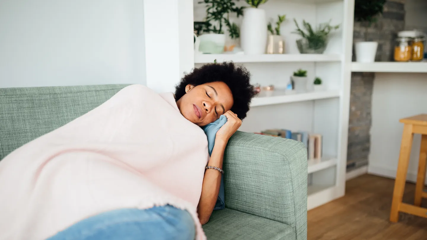 Woman laying on a couch under a blanket