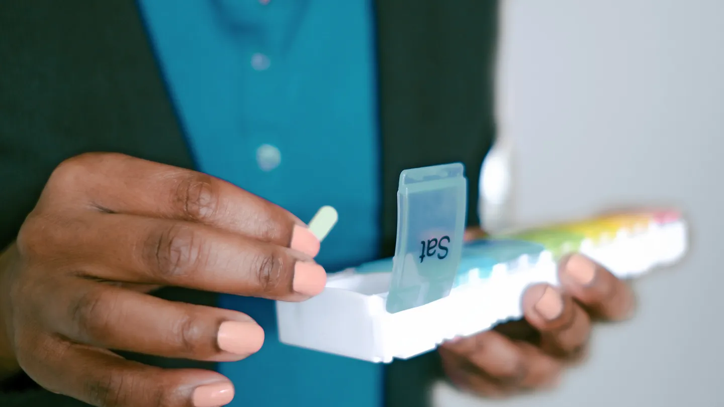 woman taking pill from pill organizer
