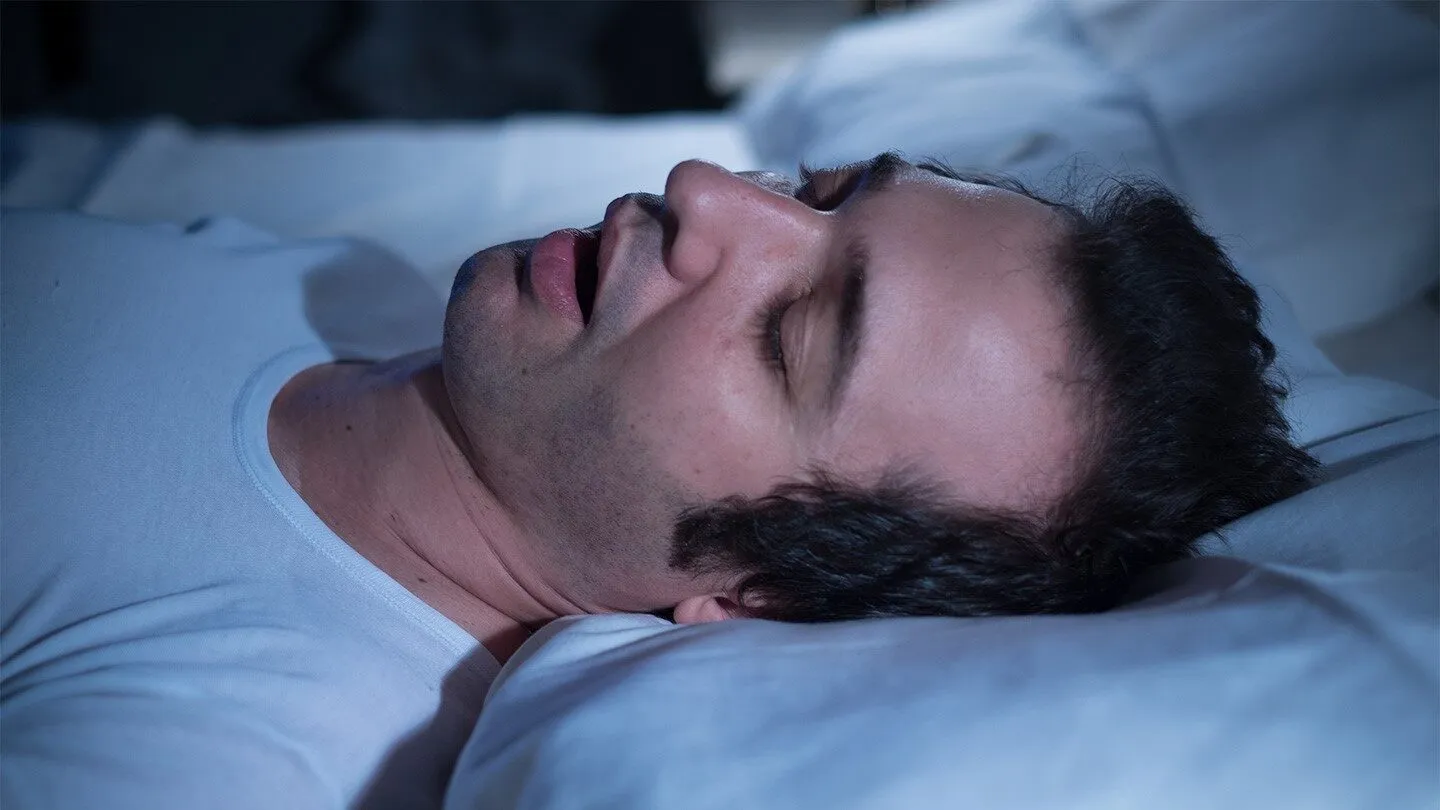 a man with sleep apnea as he sleeps in bed