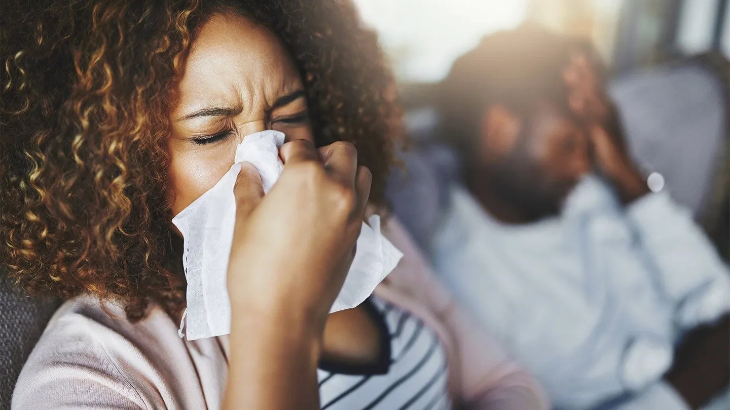 a woman blowing her nose because of allergies