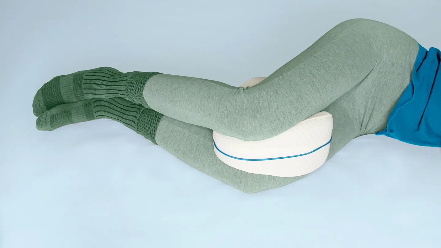 woman with a knee pillow resting on her side in bed