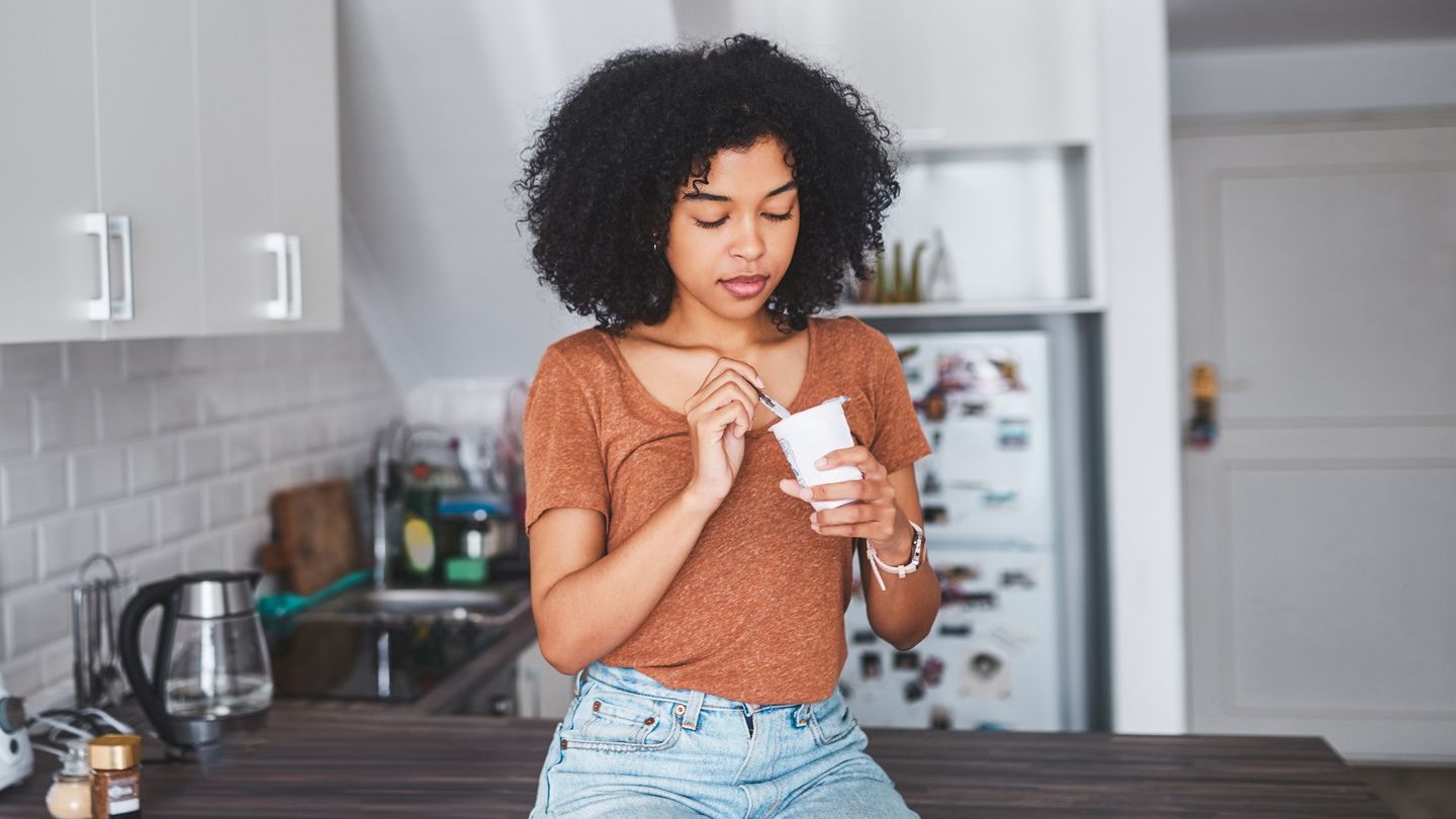 young woman eating yogurt kitchen