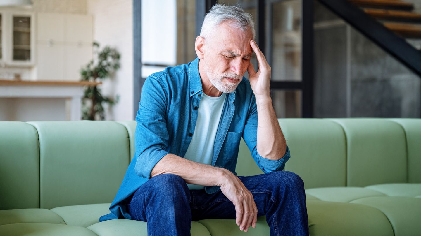 Mature white man sitting in his couch feeling fatigued