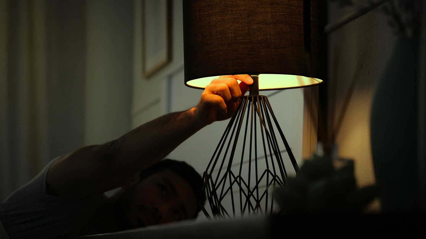 man turning off light in dim dark bedroom