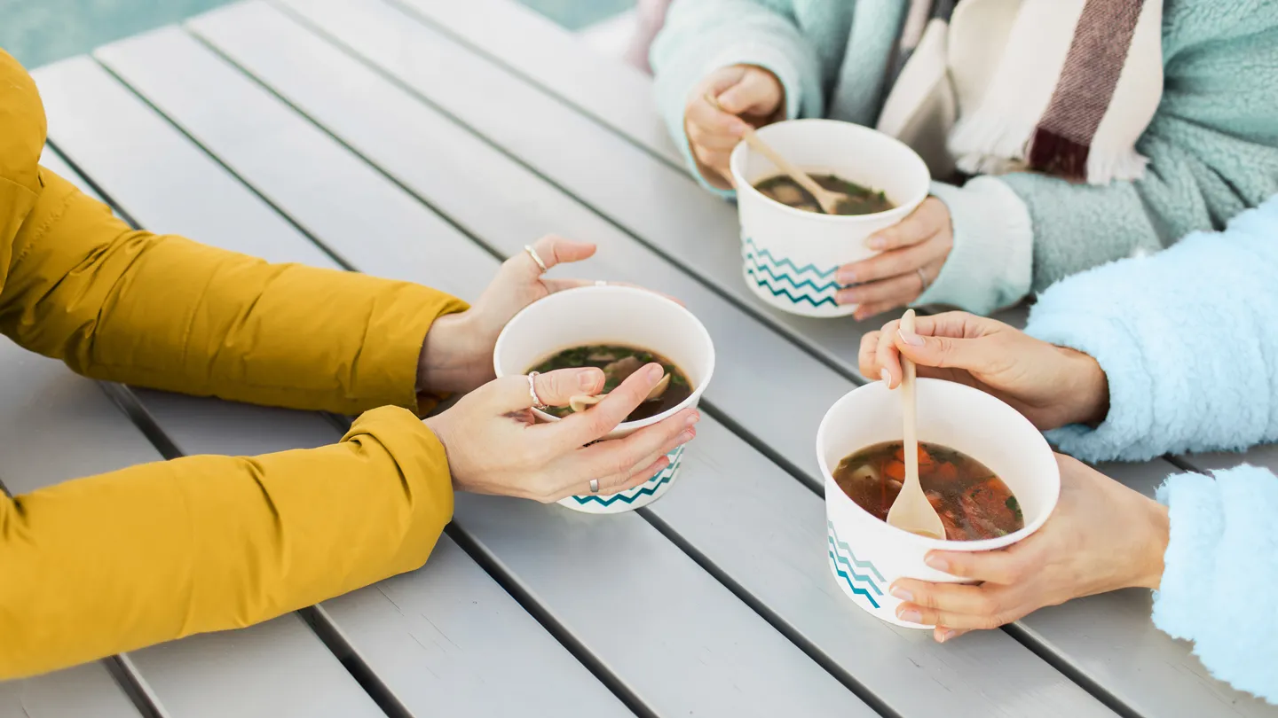 Three people have soup outside in winter