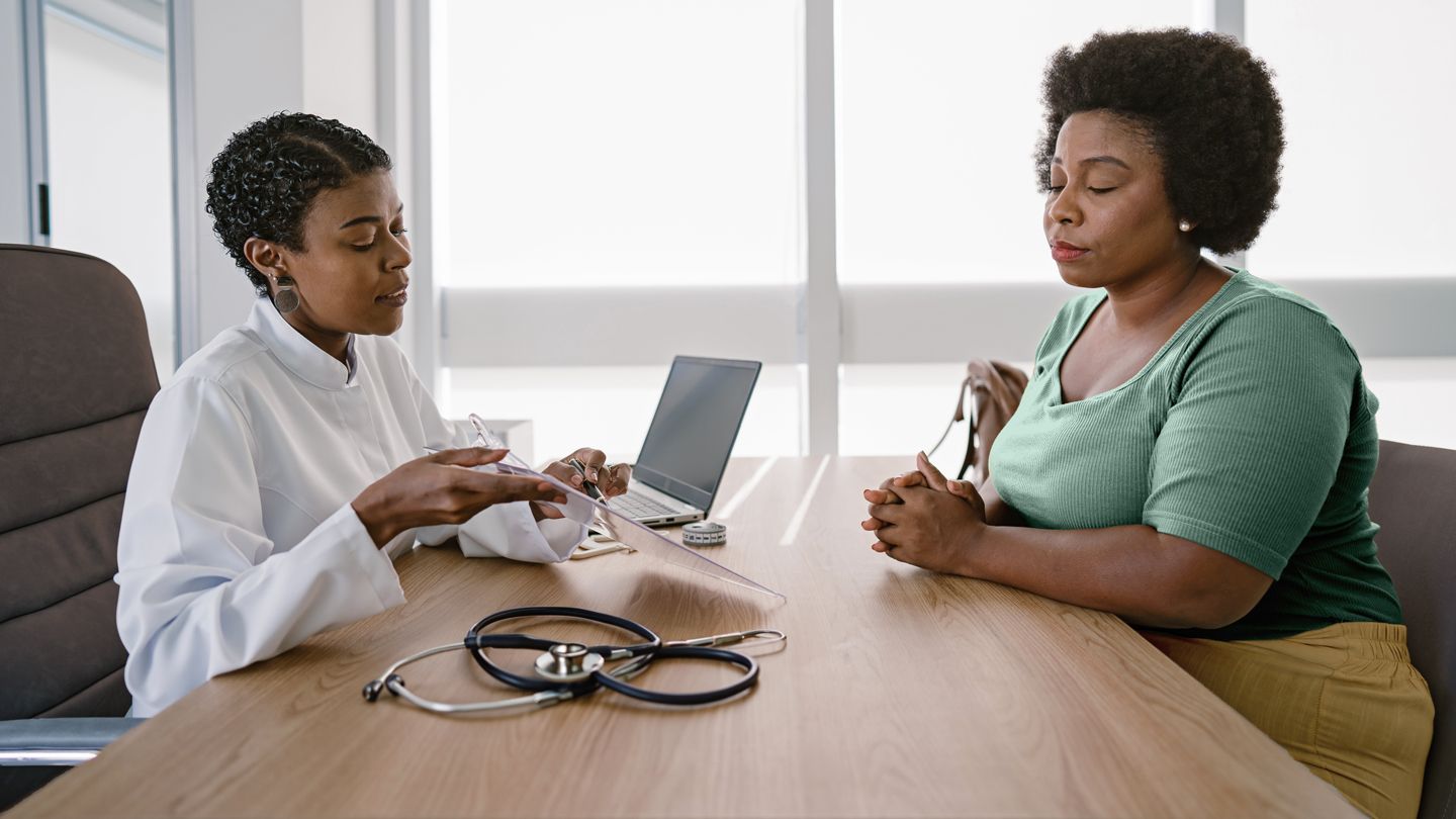 overweight mature Black patient speaking with her doctor