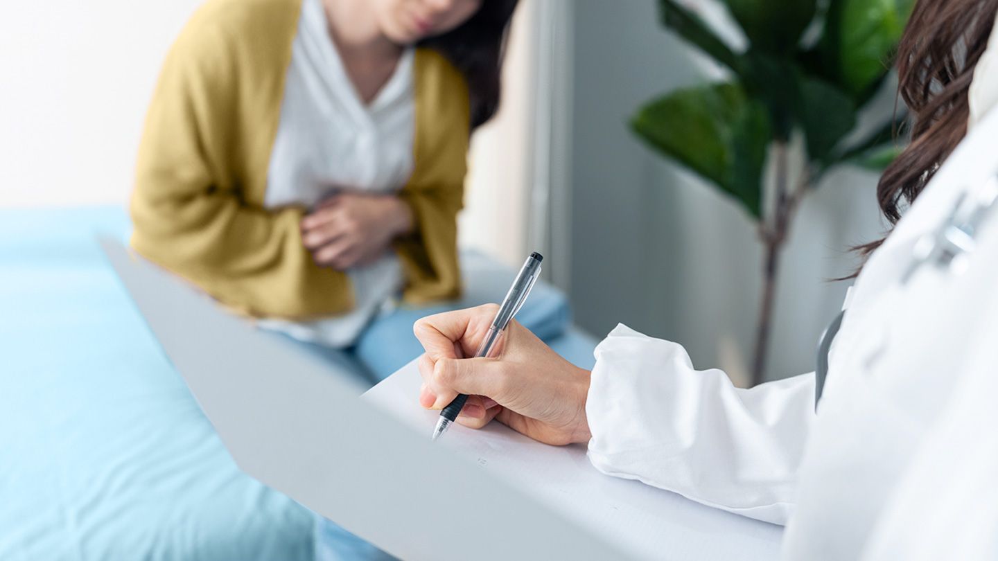 lady seated at doctors with stomach pain office talking to physician about ulcerative colitis diagnosis