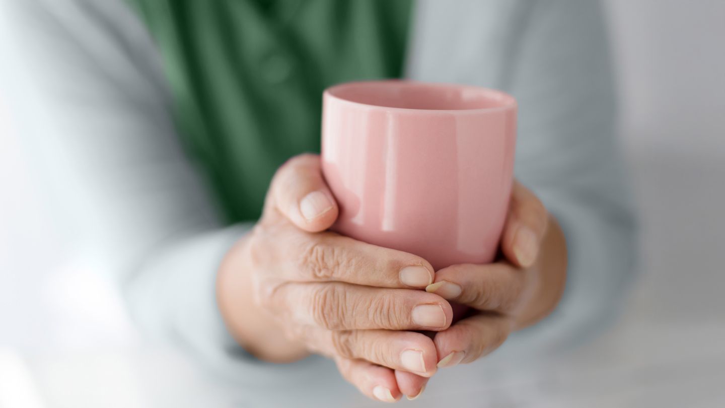 senior women's hands holding coffee mug