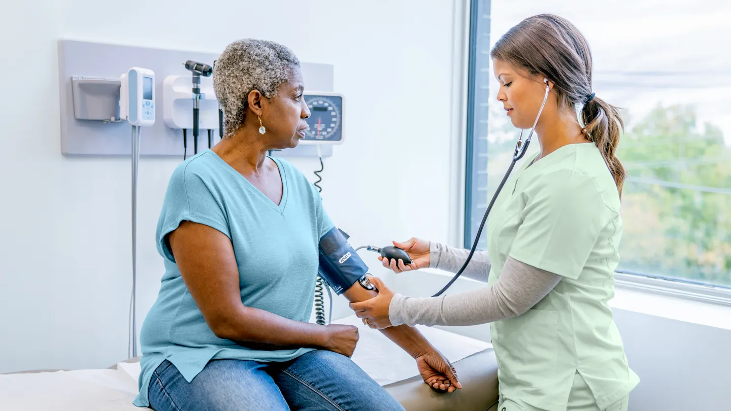 Black mature woman getting blood pressure taken by nurse