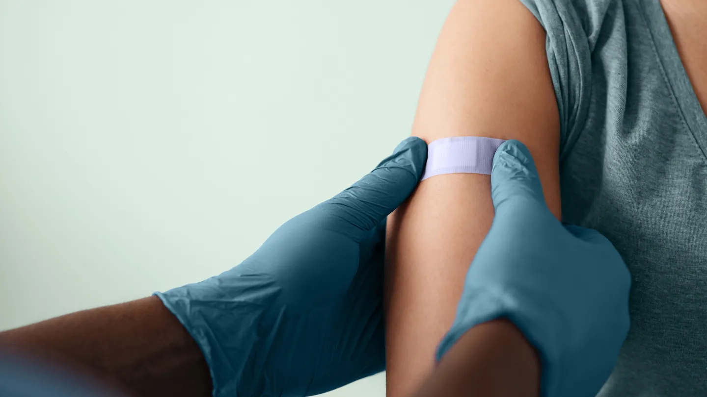 nurse putting a bandaid on patient's arm after vaccine