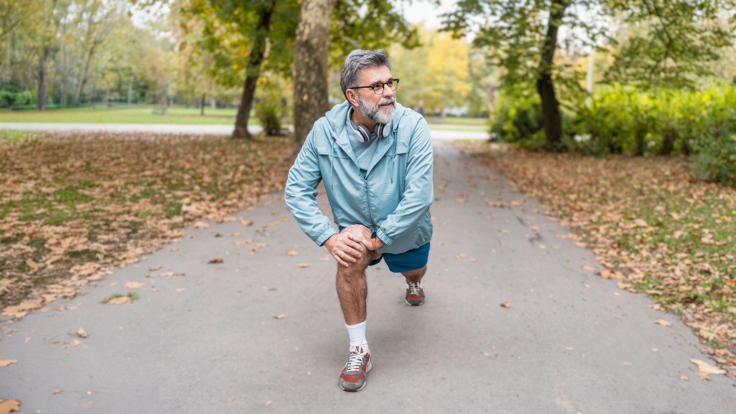 senior man stretching before a walk in the park