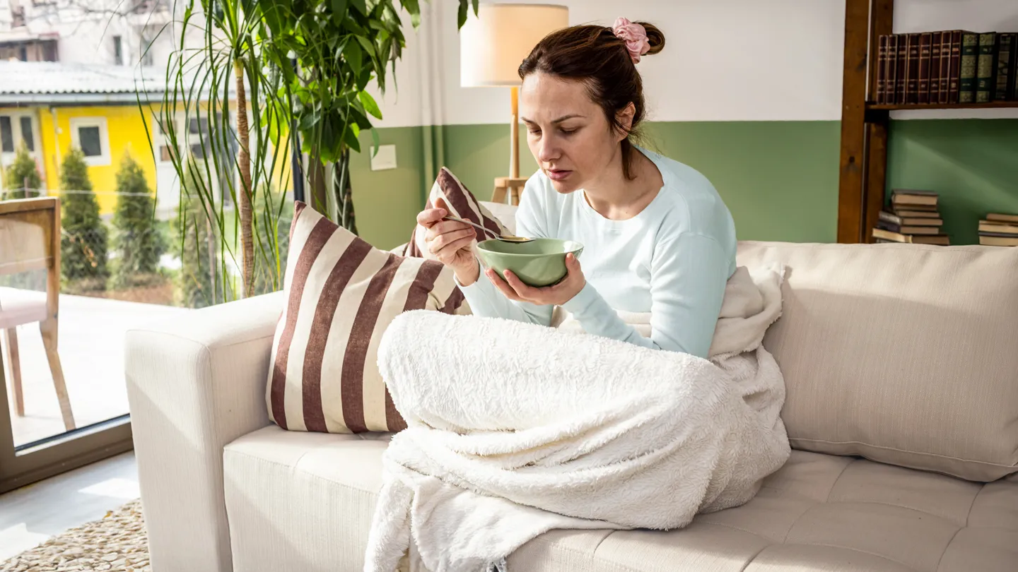 woman eating soup in couch