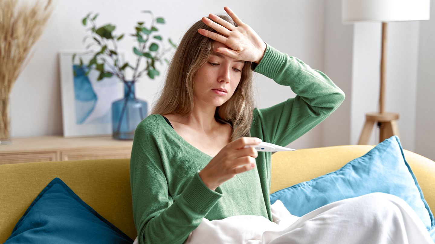 sick woman testing for a fever