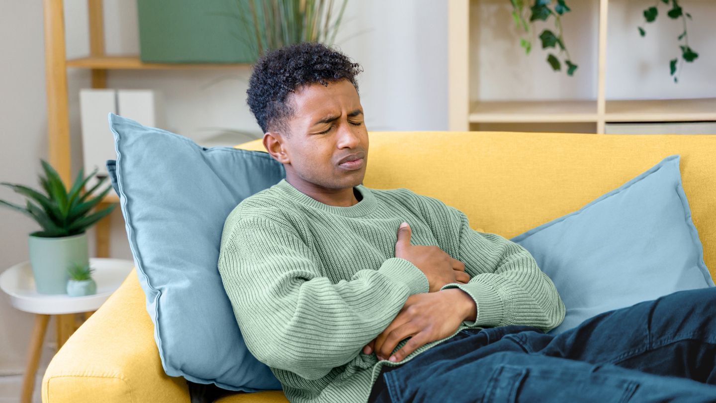 Young man laying on the couch with stomach pain