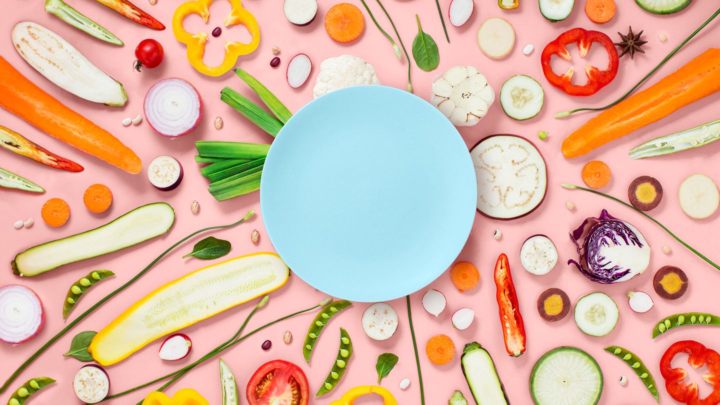assorted food vegetables chaotically dispersing around a clean blue simple dinner plate