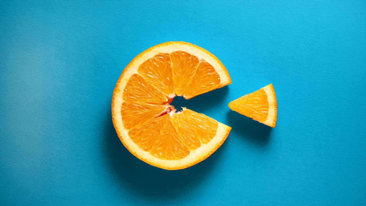 Orange slice with a wedge taken out against blue background