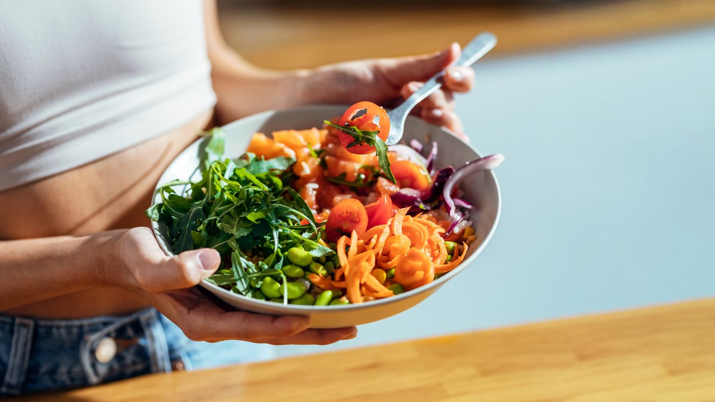 vegan bowl held by woman eating lunch in sunshine