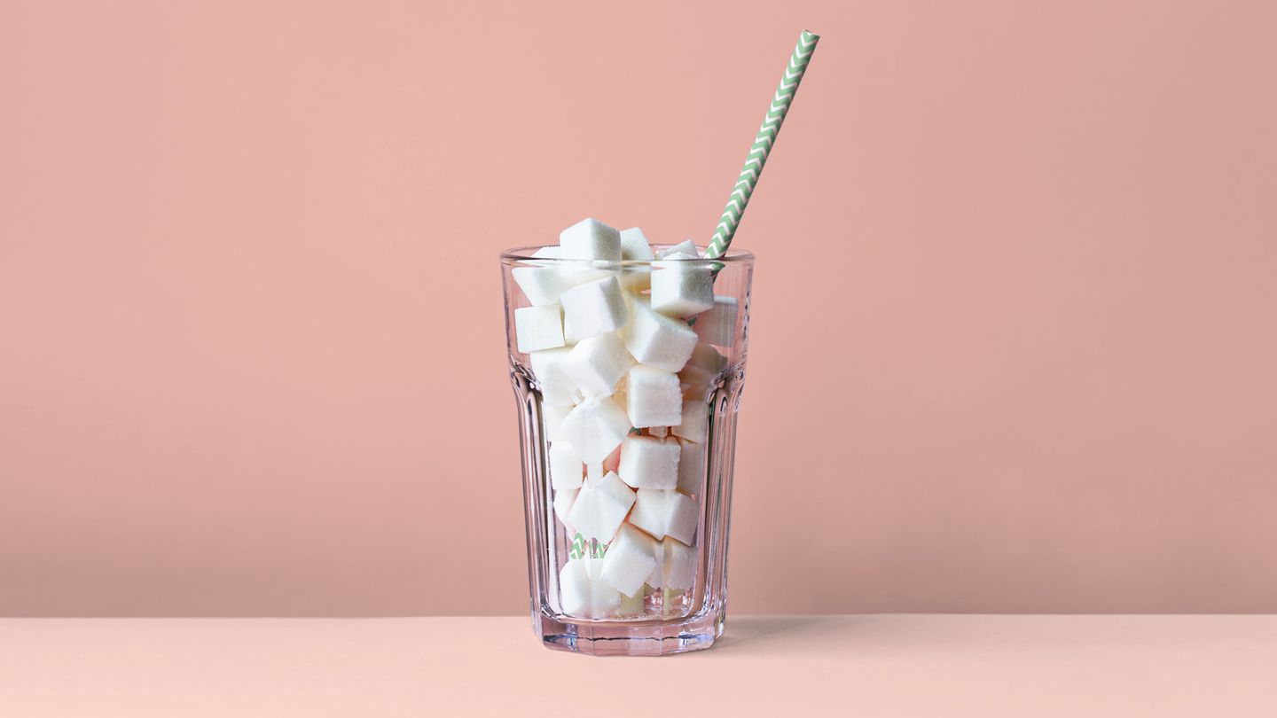 glass full of sugar cubes with striped straw