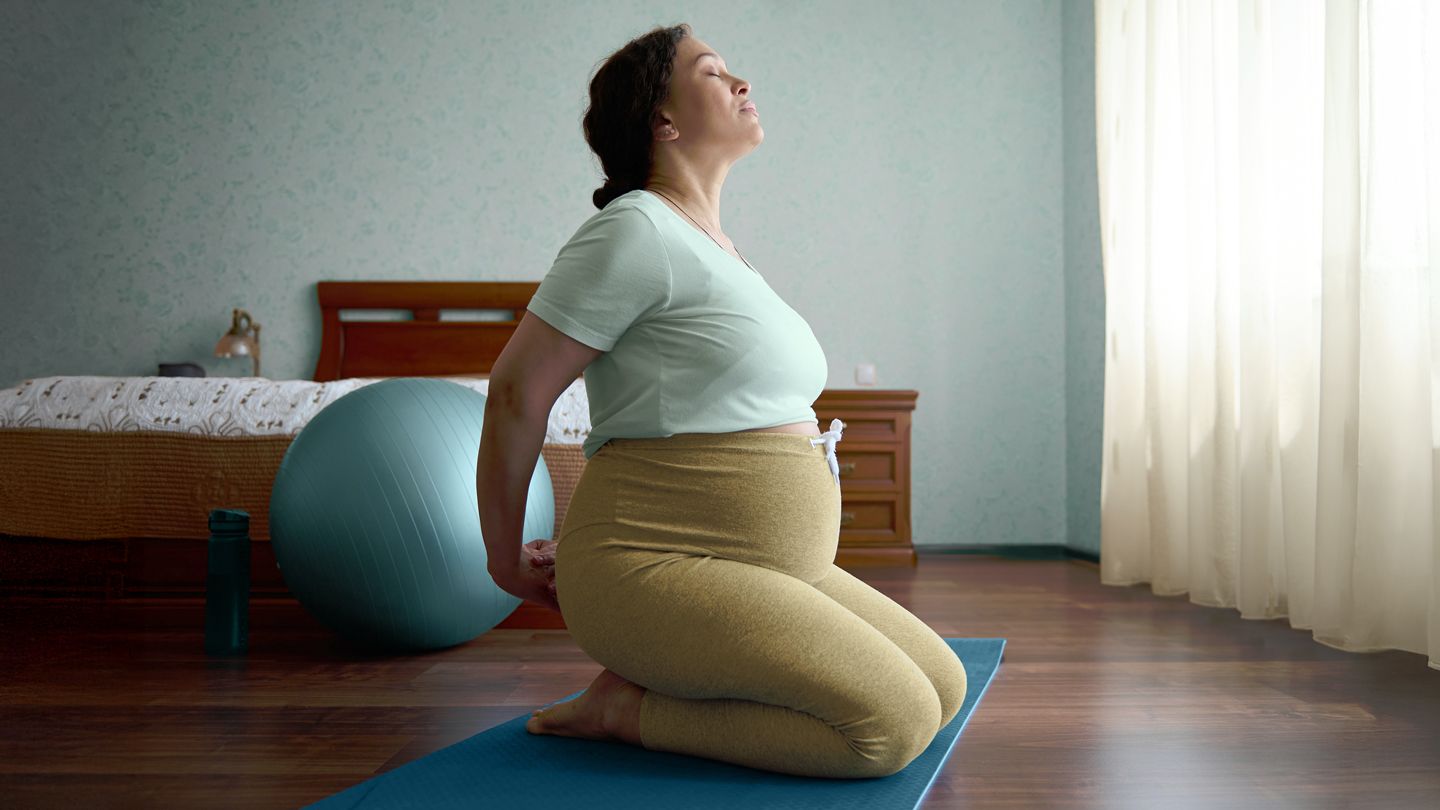 pregnant woman stretching her lower back on yoga mat