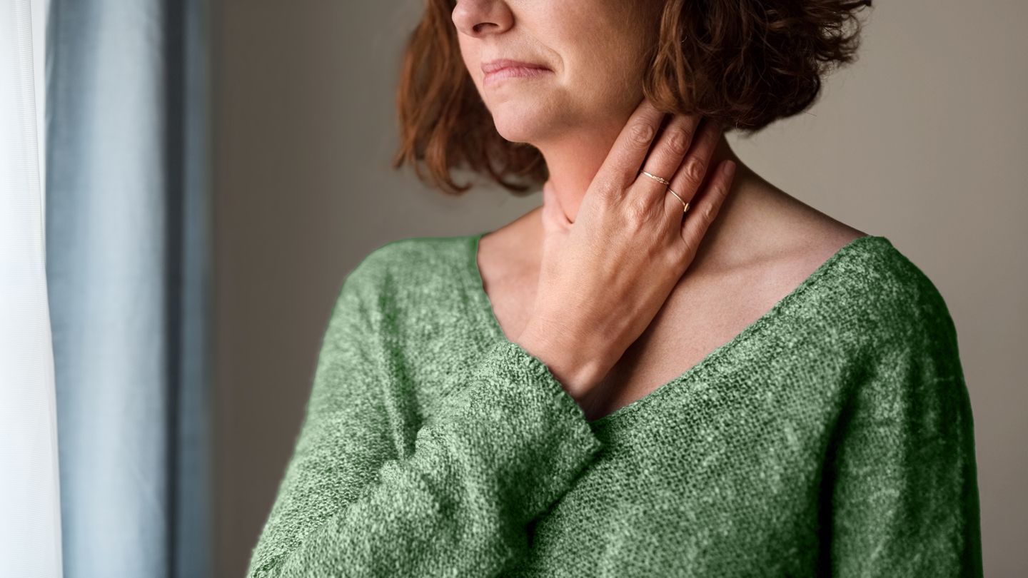 middle aged woman holding her sore throat in distress