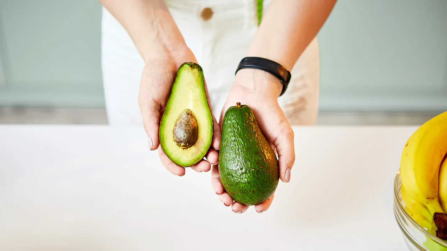woman holding cut avocado