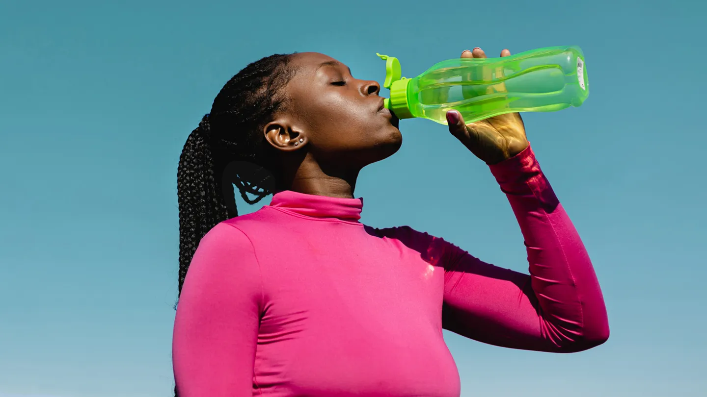 woman drinking water outdoors blue sky