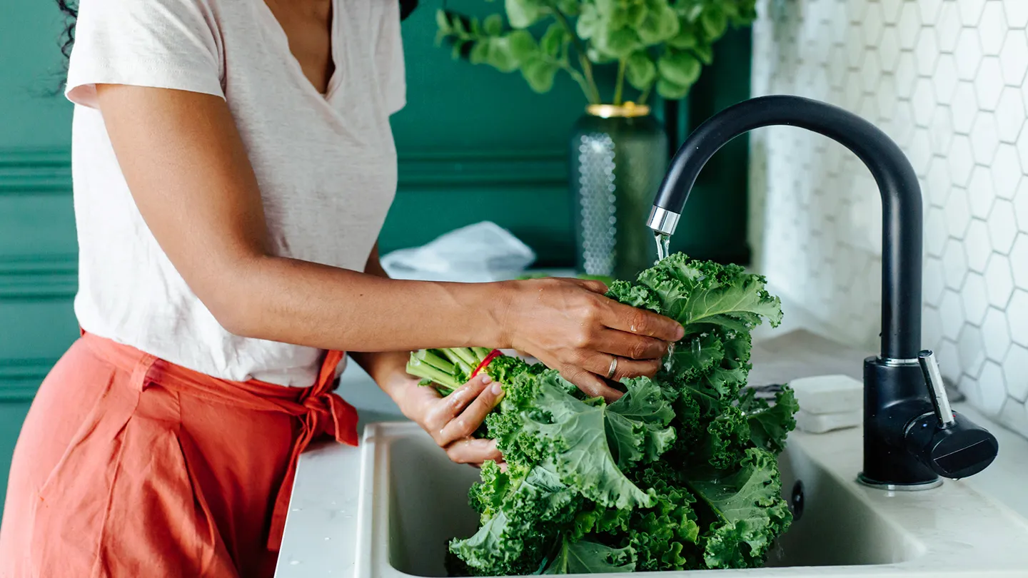 woman washing kale in sink