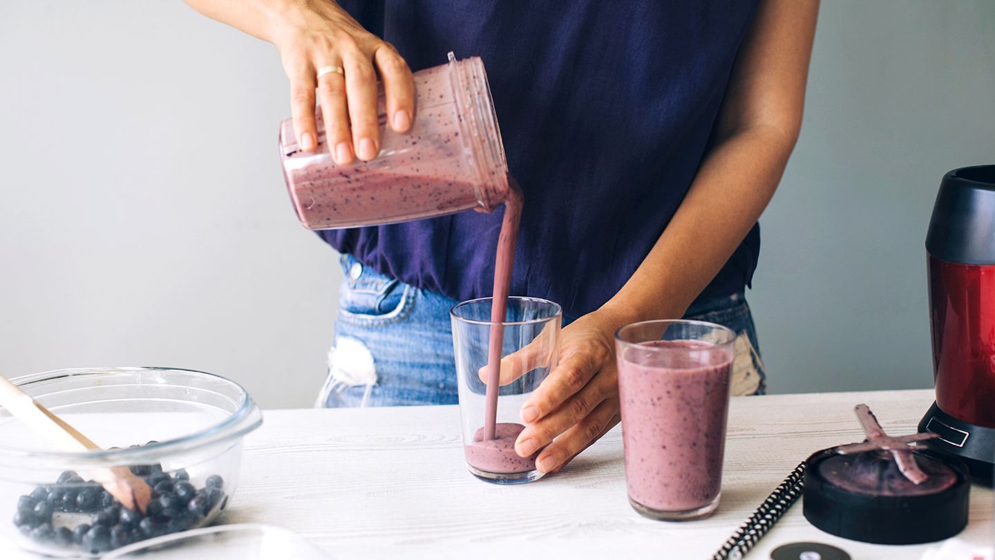 woman pouring blueberry smoothie