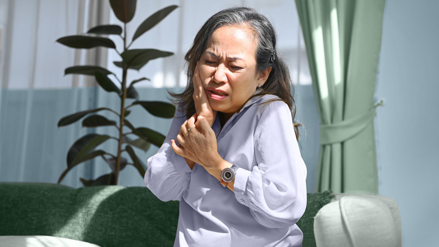 mature woman holding her jaw in pain