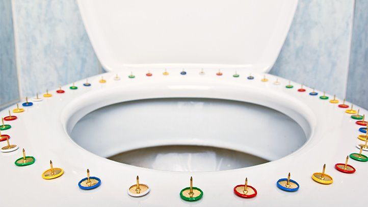 a toilet seat lined with thumbtacks, representing the pain of hemorrhoids