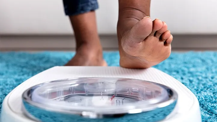 a person with GERD checking their weight on a scale