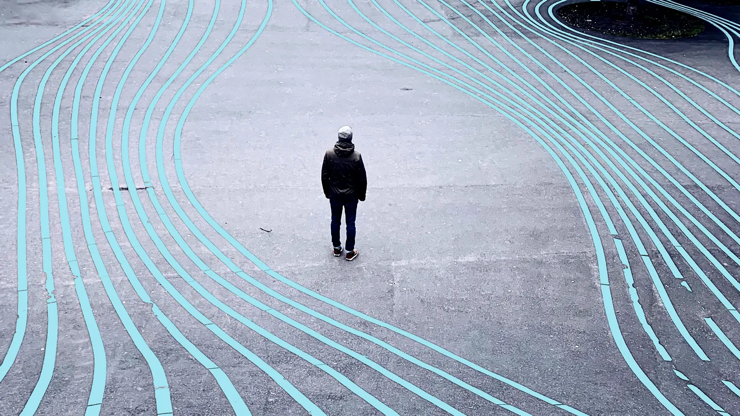 Rear view of a man standing on a city street surrounded by parallel lines moving away from him