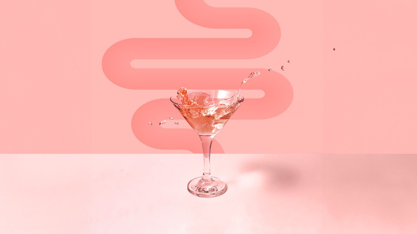 sugary pink cocktail on coral background with a simple intestines shape behind