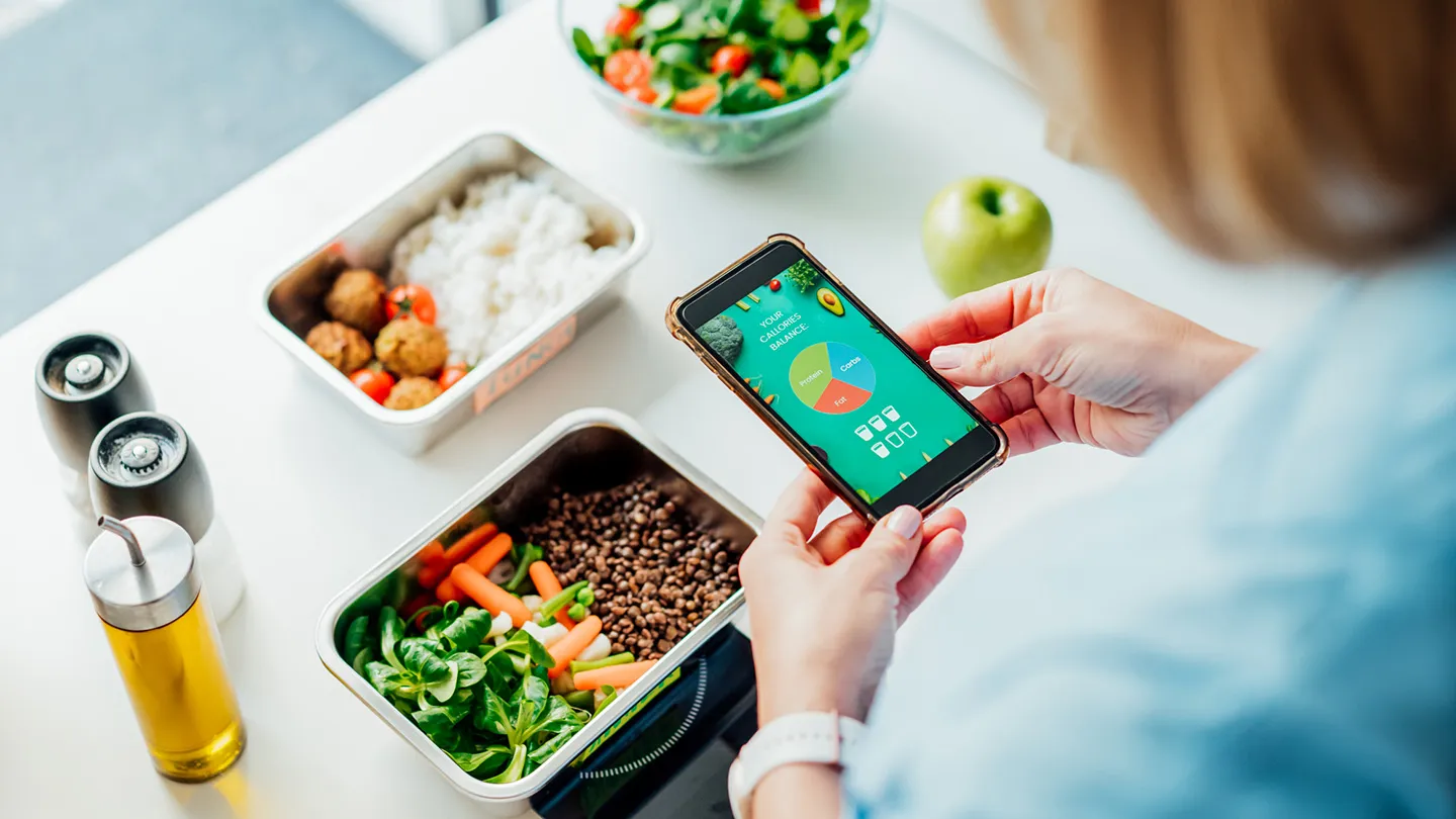 woman weighing and calculating protein intake on phone application