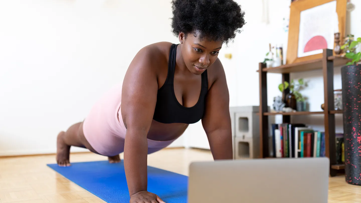 woman doing push up in living room on yoga mat